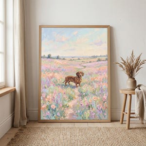 May include: A framed oil painting depicts a brown dachshund standing in a field of colorful wildflowers. The artwork features a path leading through the flowers, under a sky with soft clouds. The painting is in a light wooden frame.