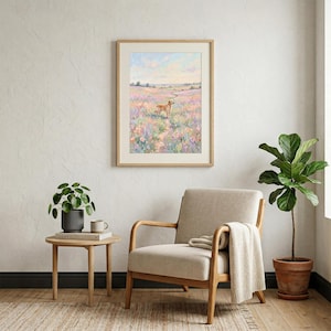 May include: A framed landscape painting depicting a golden retriever in a field of wildflowers. The artwork is in a light wooden frame. The room includes a neutral-toned chair, a small table, and a potted plant, creating a serene atmosphere.