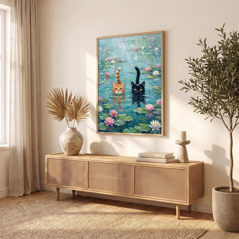 May include: A rectangular wall art print featuring an oil painting of an orange tabby cat and a black cat swimming in a pond filled with green lily pads and pink and white water lilies. The cats have their heads and tails visible above the water.