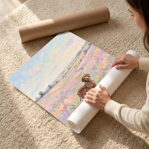 May include: A rolled-up art print featuring a dog in a field of flowers. The print is being unrolled, revealing a colorful landscape with pastel hues. A brown cardboard tube rests nearby.