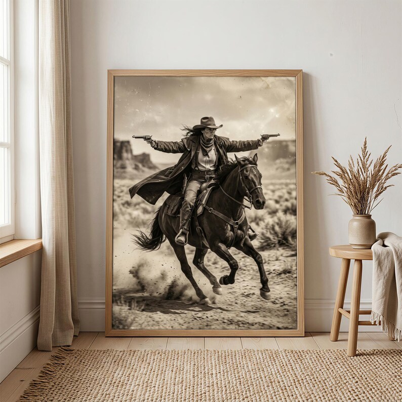 May include: Sepia-toned framed print of a person riding a horse through a desert landscape. The person, wearing a cowboy hat and duster, holds two pistols. The horse is galloping, kicking up dust. The artwork evokes a Western theme.