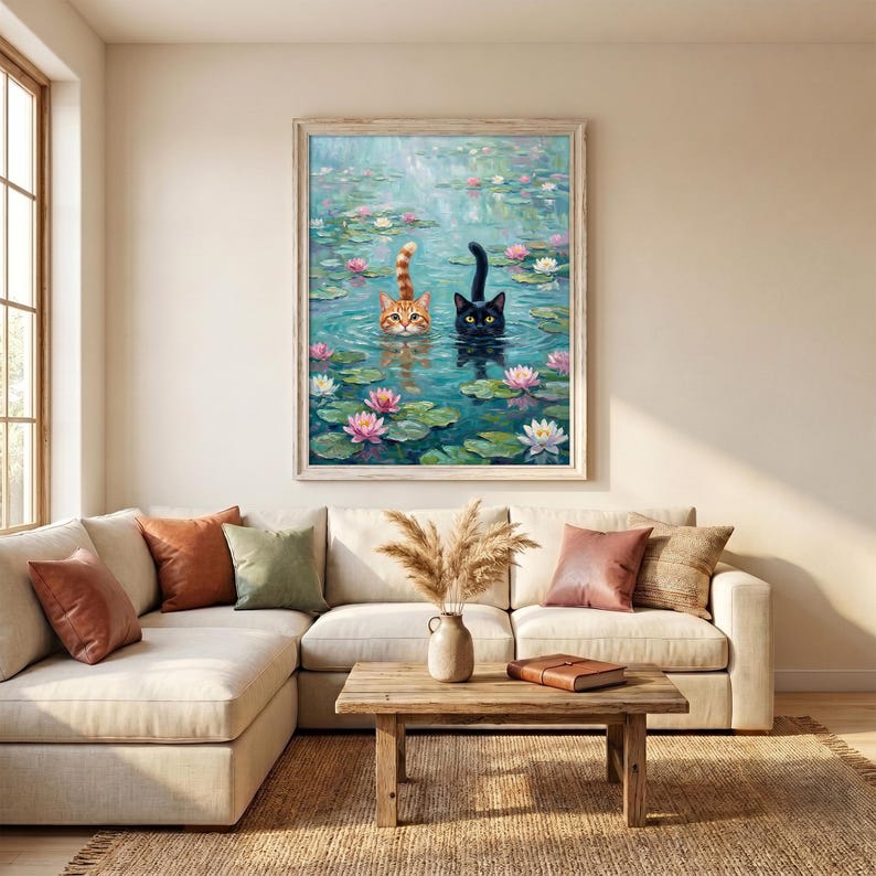 May include: A framed wall art print depicting a ginger tabby cat and a black cat swimming in a pond filled with green lily pads and pink and white water lilies. The cats are positioned side by side with their heads above the water surface.