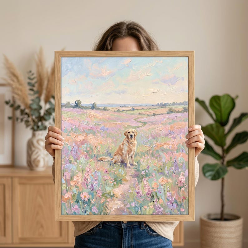 May include: A framed painting of a Golden Retriever dog sitting in a field of colorful flowers. The artwork features a light brown wooden frame and a pastel color palette, with a path leading through the flowers.