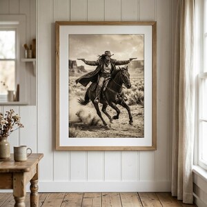 May include: Sepia-toned framed print of a person on horseback, arms outstretched, holding two pistols. The rider wears a hat and long coat, galloping across a desert landscape. The image evokes a classic Western theme.