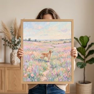 May include: A framed painting depicting a golden retriever in a field of flowers. The artwork uses a pastel colour palette with pink, purple, and blue hues. The dog is the central figure, set against a landscape with a path winding through the flowers.