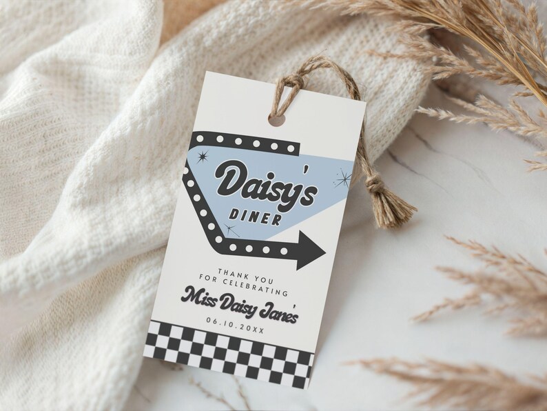 May include: A retro-style gift tag with the text "Daisy's Diner" in a stylized font, featuring a light blue arrow design. The tag includes the text "Thank you for celebrating Miss Daisy Janes" and a black and white checkered pattern.