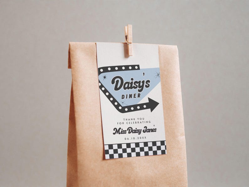 May include: A brown paper bag with a tag that reads "Daisy's Diner" in a retro font. The tag has a black arrow and a checkered pattern at the bottom. A wooden clip holds the tag in place.