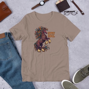 Könnte beinhalten: Ein beiges T-Shirt mit einer farbenfrohen Illustration eines sich aufbäumenden Pferdes, verziert mit detaillierten Mustern und einer fließenden Mähne. Der Text "GYPSY SOUL" ist über dem Pferd aufgedruckt. Das T-Shirt ist aus weichem Material.