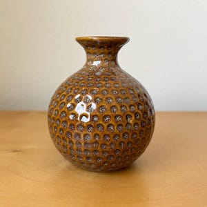 May include: A set of three ceramic mugs with a speckled, matte finish. The mugs are in shades of cream, light gray, and dark gray. Each mug has a simple, minimalist design and a rounded handle.