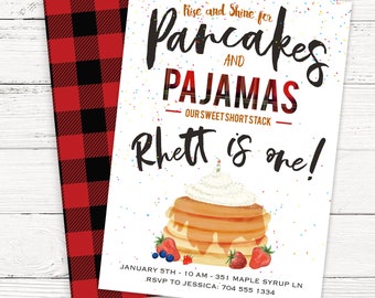 May include: A white invitation with colorful confetti sprinkles. The invitation is for a "Pancakes and Pajamas" party for a child named Rhett turning one year old. The invitation includes a cartoon illustration of a stack of pancakes with whipped cream and berries.