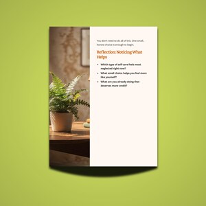 May include: A white paper with text on a green background. The text reads "Reflection: Noticing What Helps" and includes questions about self-care. A potted fern sits on a wooden table, with a blurred background.