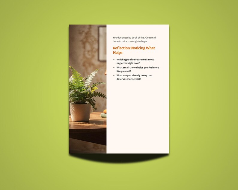 May include: A white paper with text on a green background. The text reads "Reflection: Noticing What Helps" and includes questions about self-care. A potted fern sits on a wooden table, with a blurred background.