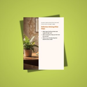 May include: A white card with text on a green background. The text reads "Reflection: Noticing What Helps" and lists questions about self-care. A potted fern sits on a wooden table, with a blurred background.