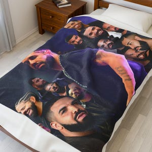 May include: A navy blue blanket featuring a collage of images of a man with a beard and various hairstyles. The blanket is on a bed with a white pillow and a wooden nightstand.