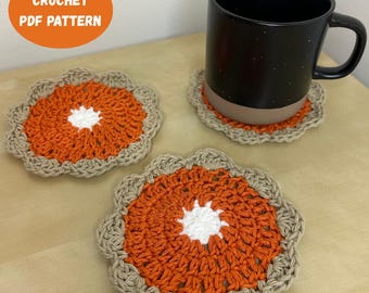 May include: Three handmade crochet coasters in a pie-like design. The coasters feature an orange center with a white starburst, surrounded by a tan border. A black mug sits on one coaster. The image includes text that says "CROCHET PDF PATTERN".