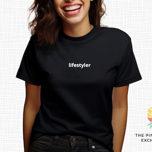 May include: Black t-shirt with the word "lifestyler" printed in white. The shirt is a crew neck style and is being worn by a person. The Pineapple Exchange logo is visible in the bottom right corner.