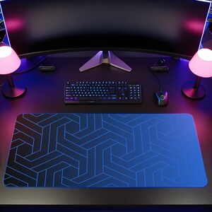 May include: A gaming desk setup featuring a curved monitor, a black keyboard, a computer mouse, and a large rectangular desk mat with a blue geometric pattern. The workspace includes two small lamps, two speakers, four potted plants, and headphones.