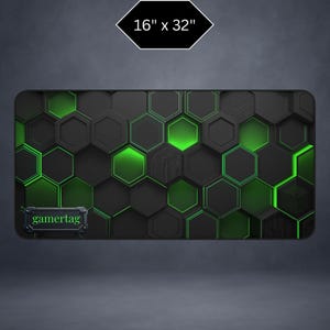 May include: Black and green gaming mouse pad with a hexagonal pattern. The pad measures 16 x 32 inches and features the text "gamertag" at the bottom. The design includes glowing green accents.