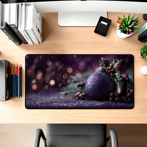May include: A purple Christmas ornament with a textured surface, holly, and berries on a decorative mousepad. The mousepad has a dark purple background with bokeh lights and a computer mouse.
