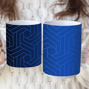 May include: Two ceramic mugs featuring a geometric pattern of interlocking lines. The left mug has a dark navy blue background with light blue lines, while the right mug has a medium blue background with darker blue lines. Both mugs have white interiors.