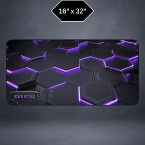 May include: A black and purple gaming mouse pad with a hexagonal pattern and the word "gamertag". The pad measures 16 x 32 inches. The design features a dark background with glowing purple accents.