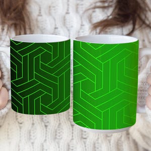 May include: Two ceramic mugs featuring a geometric pattern of interconnected lines. The left mug has a dark green background with bright green lines, while the right mug has a vibrant green background with darker green lines. Both mugs have white handles.