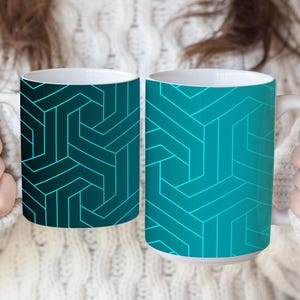 May include: Two ceramic mugs featuring a geometric pattern of interlocking lines. The left mug has a dark teal background with bright cyan lines, while the right mug has a bright cyan background with dark teal lines. Both mugs have white handles.