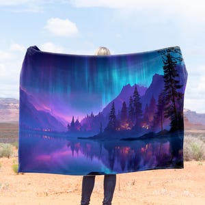 May include: A large, rectangular blanket featuring a vibrant landscape scene. The design showcases a mountain range, a reflective lake, and a forest under a colorful aurora borealis. The color palette includes shades of purple, blue, and green.