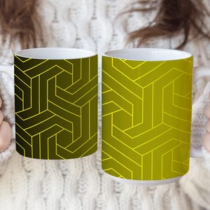 May include: Two ceramic mugs featuring a geometric pattern of interlocking lines. The left mug has a dark olive green background with bright yellow lines, while the right mug has a bright yellow background with dark olive green lines.