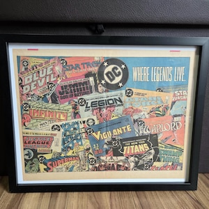 May include: Framed print featuring a collage of vintage DC Comics covers. The artwork includes titles like "Superman," "Batman," and "Justice League of America." The print has a black frame and the text "Where Legends Live."