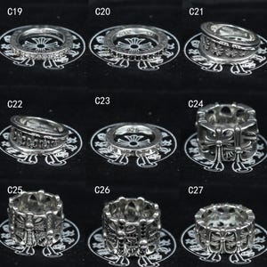Puede incluir: Una colecci&oacute;n de nueve anillos de plata etiquetados de C19 a C27, con varios dise&ntilde;os que incluyen bandas con piedras incrustadas, motivos de cruces y grabados intrincados. Cada anillo se muestra sobre una superficie negra con un logotipo.