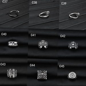 Puede incluir: Una colecci&oacute;n de nueve anillos de metal plateado etiquetados de C37 a C45. Los dise&ntilde;os incluyen bandas delgadas, estilos de clavo abiertos y bandas m&aacute;s anchas con patrones en relieve de cruces, flores y formas geom&eacute;tricas con acentos oxidados.