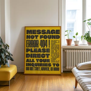 May include: A framed yellow poster with black text that reads "MESSAGE NOT FOUND ERROR 404! PLEASE DIRECT ALL YOUR INQUIRIES TO 000 NULL STREET, NOWHERE, XX 00000." The poster also includes a smaller block of text. The poster is in a room with a window.