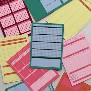 Op de afbeelding: Een verzameling kleurrijke planners in verschillende ontwerpen. De vellen bevatten kalenderindelingen, trackinggrafieken en lijsten. Kleuren zijn roze, groen, geel en oranje. De vellen zijn ontworpen voor het organiseren en plannen.