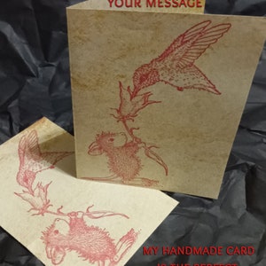 May include: A handmade card with a red hummingbird and a mouse holding onto a flower stem. The card has the text "Your Message" on the front and "My handmade card is the perfect accompaniment to your thoughtful gift" on the back.