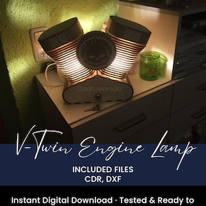 May include: A V-Twin engine lamp made of layered cardboard, with a skull emblem in the center. The lamp has a warm glow, and the text "V-Twin Engine Lamp" is visible. The base has the text "Cadfusionlab".