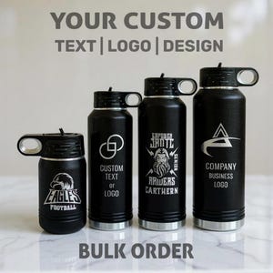 Four black water bottles of varying heights lined up on a white marble surface, each engraved with different custom logos and text.