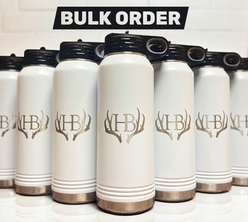 Puede incluir: Botellas de agua aisladas blancas con tapas negras y bases doradas. Cada botella presenta un monograma dorado con las letras "HB" y un dise&ntilde;o de cornamenta. El texto "BULK ORDER" se muestra en la parte superior.