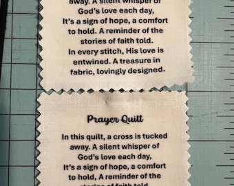 May include: Two off-white fabric squares with the text "Prayer Quilt" and a poem printed in black. The squares have a decorative, scalloped edge. The poem speaks of faith, hope, and comfort.
