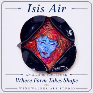 May include: A sculpture titled Isis Air, an A.C.I.D. sculpture, Where Form Takes Shape, Windwalker Art Studio. The piece features a central painted face with blue skin and red hair, framed by four glossy black, curved, petal-like metal panels.