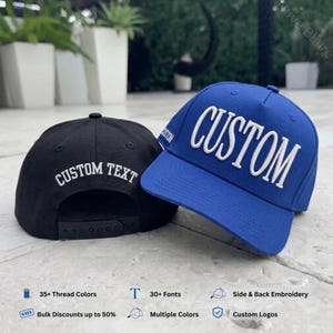 May include: A blue baseball cap with the word CUSTOM embroidered in white on the front and a black baseball cap with the words CUSTOM TEXT embroidered in white on the back, featuring an adjustable snapback closure on the black cap.