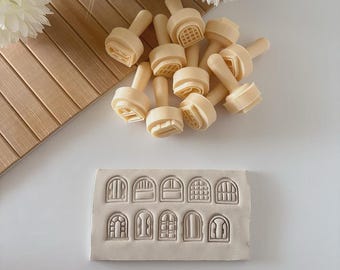May include: A collection of beige cookie stamps and a rectangular mold with various window designs. The stamps have handles and detailed window patterns. The mold features a variety of window shapes, perfect for baking and crafting.