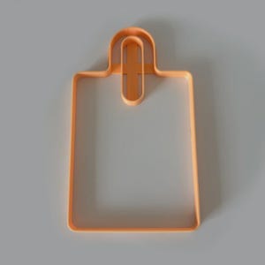 May include: An orange plastic cookie cutter in the shape of a shopping bag. The cutter has a rectangular body with a handle at the top. The design is simple and clean, perfect for baking.