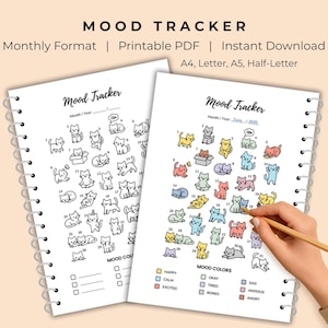 Op de afbeelding: Twee mood trackers met spiraalbinding met kattenillustraties. Eén is zwart-wit, de andere is gekleurd. De tekst "MOOD TRACKER" staat bovenaan. De gekleurde tracker toont een hand die een pen vasthoudt en naar een kattenillustratie wijst.