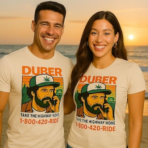 May include: Two people wearing matching cream-colored t-shirts with a graphic. The graphic features a man in a green and white hat, with the word "DURER" above and the text "TAKE THE HIGHWAY HOME 1-800-420-RIDE" below. The background is a sunset.