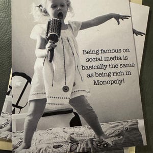May include: Black and white photograph of a young child holding a hairbrush like a microphone, singing with their mouth open. The image includes the text: "Being famous on social media is basically the same as being rich in Monopoly!"