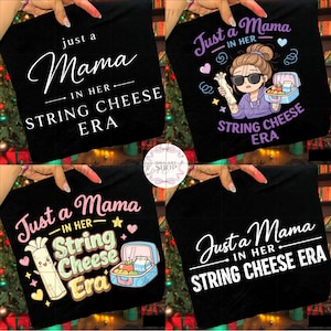 May include: Black t-shirts with the text "Just a Mama in Her String Cheese Era" in white script. One shirt features a cartoon woman with sunglasses, string cheese, and a lunchbox. Other shirts have similar designs.