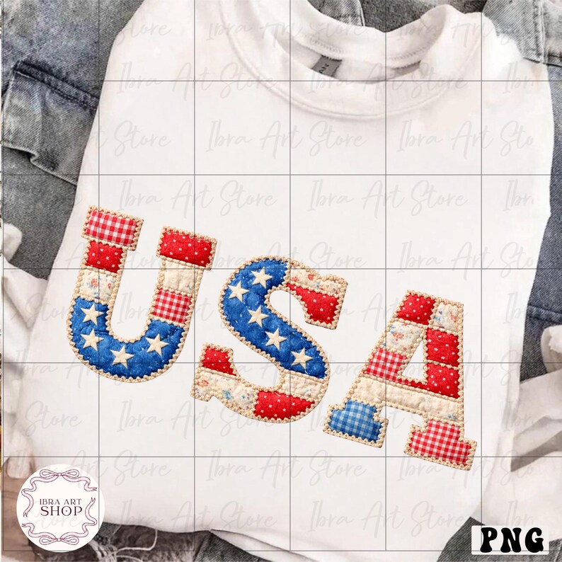 May include: White sweatshirt with the word "USA" in a patchwork design. The letters feature red, white, and blue patterns, including stars and stripes, evoking an American flag theme. The sweatshirt is folded on a denim surface.