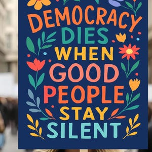 以下が含まれることがあります： 「DEMOCRACY DIES WHEN GOOD PEOPLE STAY SILENT」というカラフルな文字が書かれた濃い青色の看板。オレンジ、赤、黄色、青の花と葉のイラストで飾られています。看板は人が持っています。