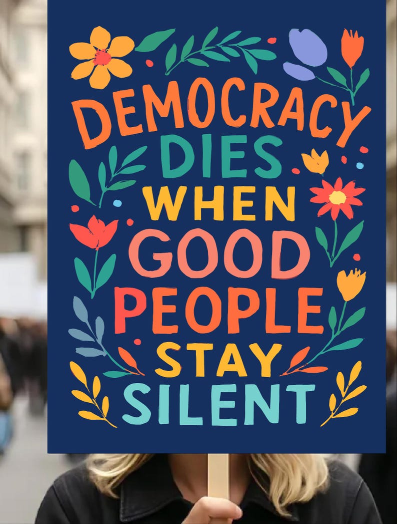 以下が含まれることがあります： 「DEMOCRACY DIES WHEN GOOD PEOPLE STAY SILENT」というカラフルな文字が書かれた濃い青色の看板。オレンジ、赤、黄色、青の花と葉のイラストで飾られています。看板は人が持っています。